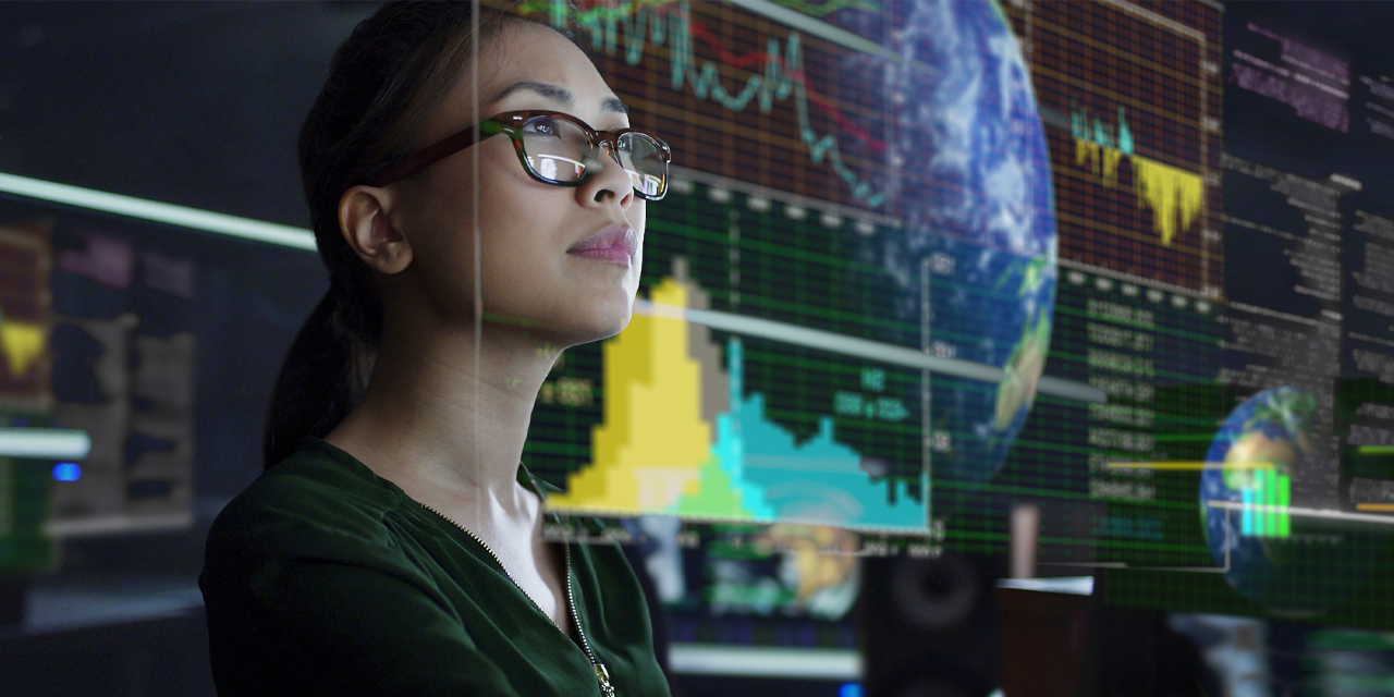 Jeune femme asiatique regardant voir à travers les données mondiales et environnementales tout en étant assise dans un bureau sombre.