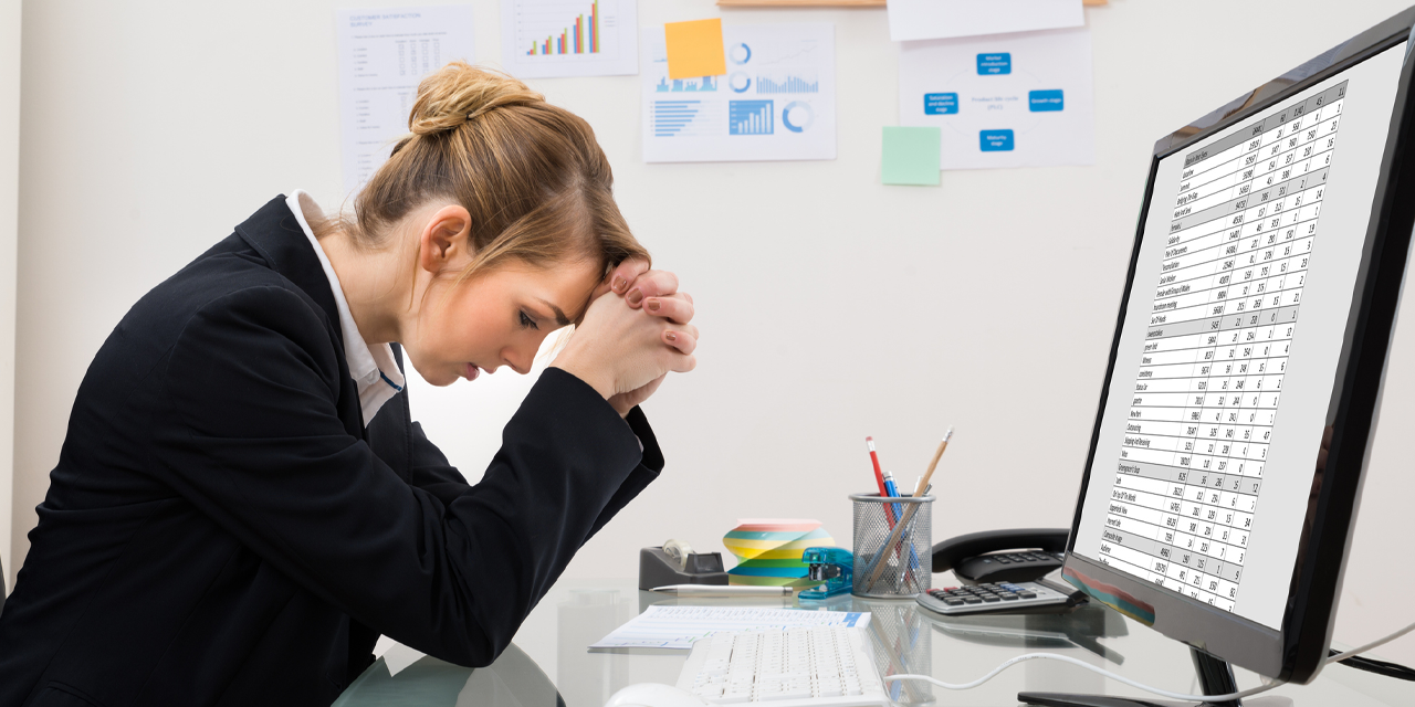 Femme blonde assise à son bureau frustrée lors de l'utilisation de feuilles de calcul 